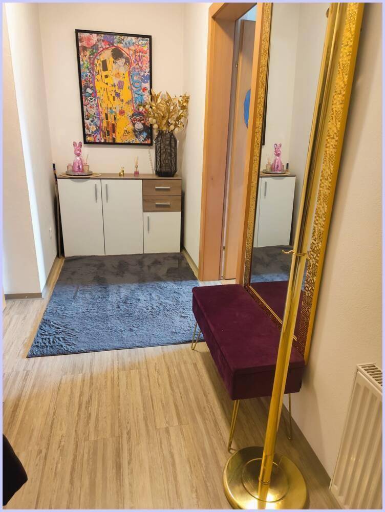 Moderner Flur mit Laminatboden, Spiegel und dekorativen Elementen.