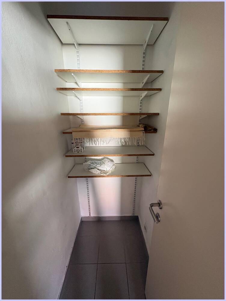 Kleiner Abstellraum mit Regalsystem und Fliesenboden, ideal für zusätzlichen Stauraum.