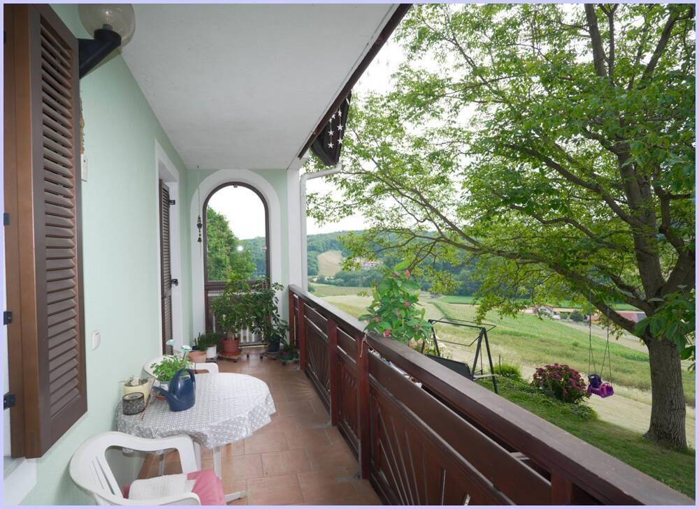 Langer Balkon mit Holzbalkonbrüstung und Sitzgelegenheiten, bietet einen weiten Blick auf die grüne Landschaft.