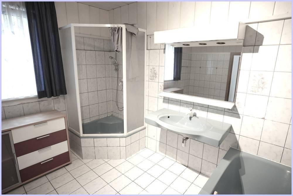 Geräumiges Badezimmer mit Duschkabine, Waschbecken und einem Fenster für Tageslicht.