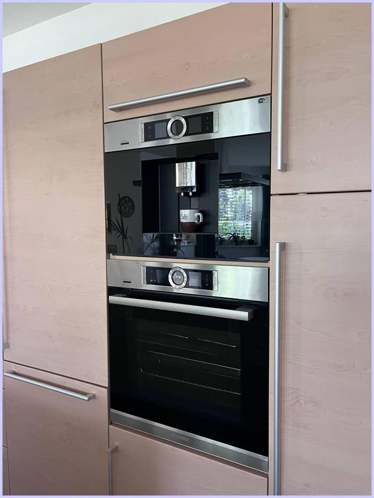 Moderne Einbauküche mit integrierter Kaffeemaschine und Backofen in hellen Holzfronten.