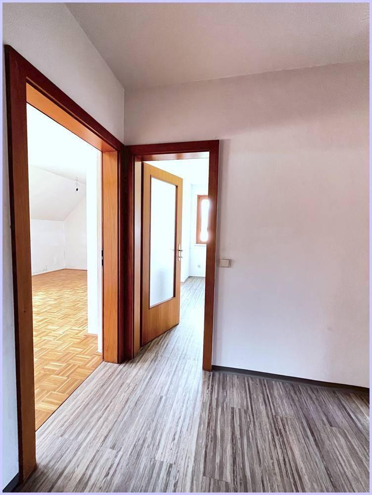 Heller Flur mit Laminatboden und Blick in angrenzende Räume mit Parkett.