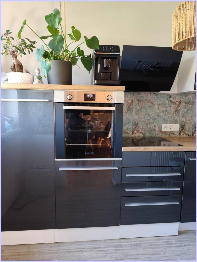 Moderne Küche mit dunklen Hochglanzfronten, Backofen und Kaffeemaschine.