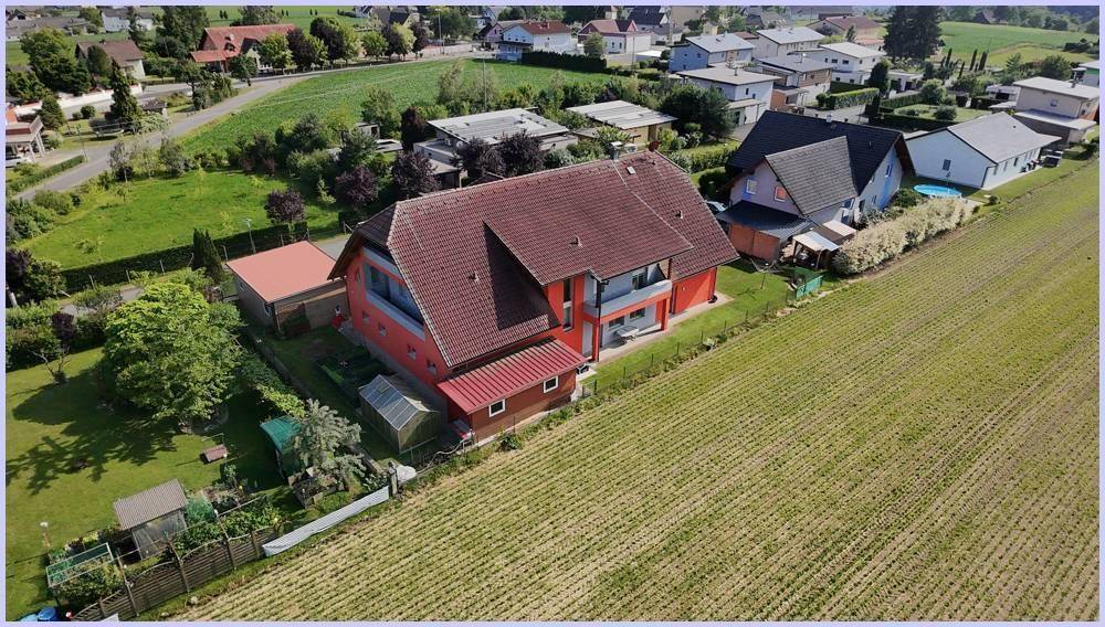 Rückwärtige Luftaufnahme des Hauses mit Garten, Gewächshaus und angrenzenden Feldern.