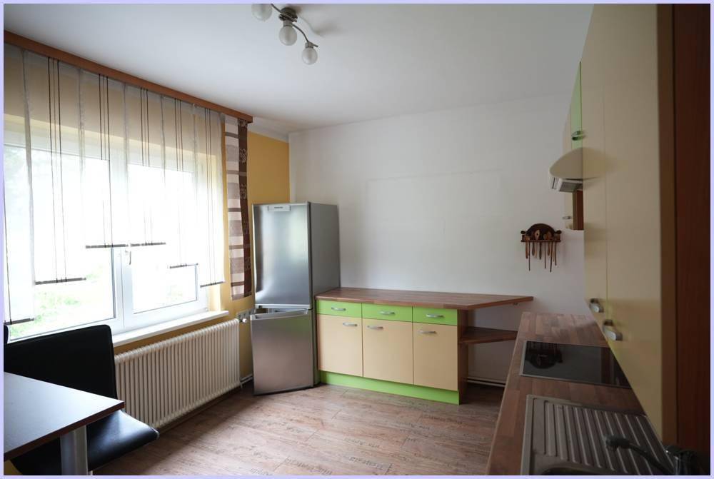 Küchenbereich mit Fenster, Kühlschrank und Arbeitsfläche, gut beleuchtet.