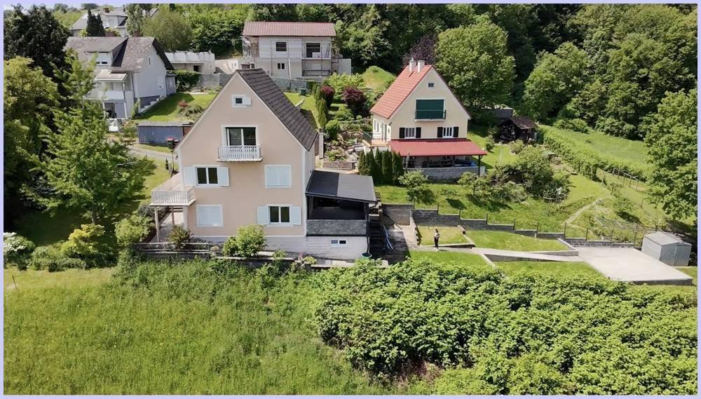 Zwei Häuser in ländlicher Umgebung mit Gärten und weitem Blick auf die Landschaft.