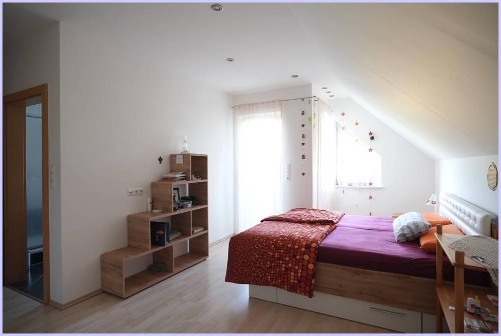 Gemütliches Schlafzimmer im Dachgeschoss mit schrägen Wänden und hellem Laminatboden.