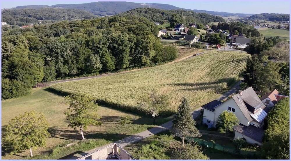 Luftaufnahme der weiten Felder und Wälder, die das Anwesen umgeben, mit einem Haus im Vordergrund.