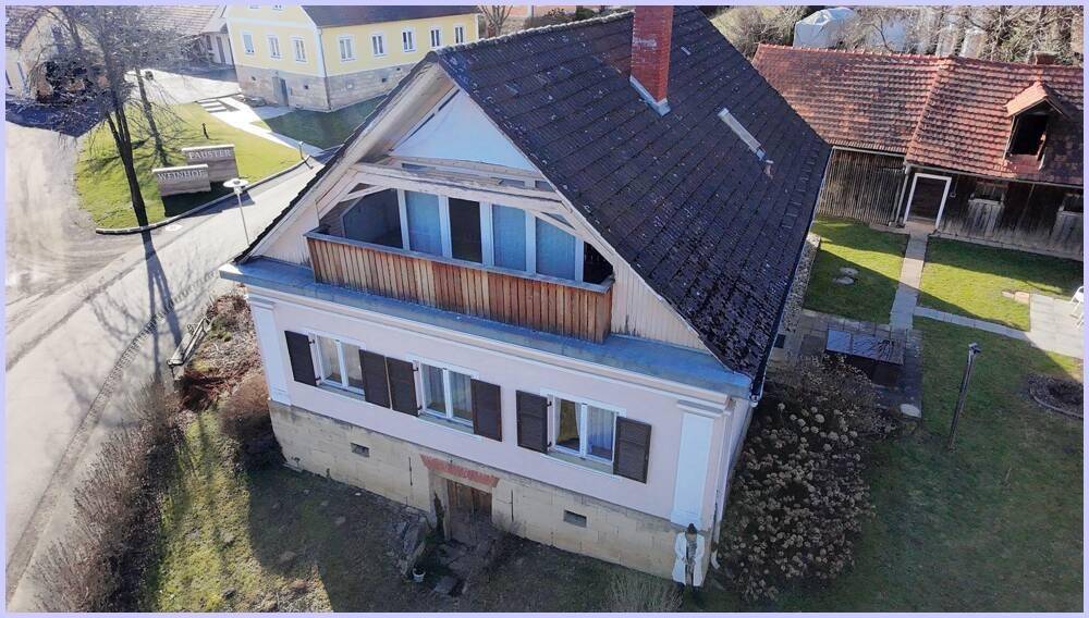 Luftaufnahme des Haupthauses mit Satteldach, Balkon und umliegendem Grundstück in ländlicher Umgebung.
