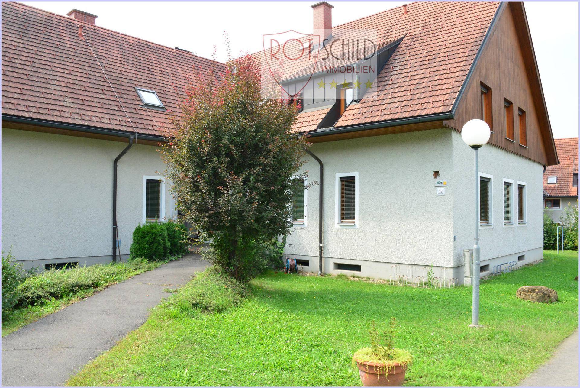 Außenansicht eines Wohnhauses mit Satteldach, Garten und gepflegter Rasenfläche.