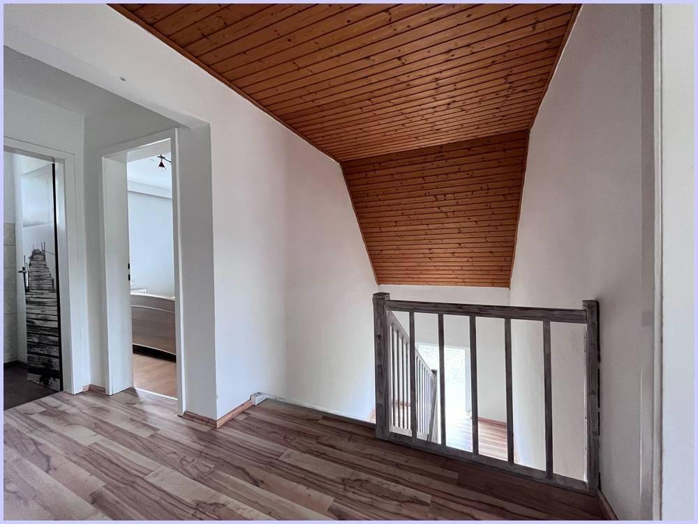 Heller Flur im Obergeschoss mit Holzdecke und Blick auf das Treppenhaus.