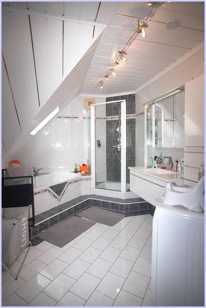 Helles Dachgeschoss-Badezimmer mit Badewanne, Duschkabine und Waschmaschine.
