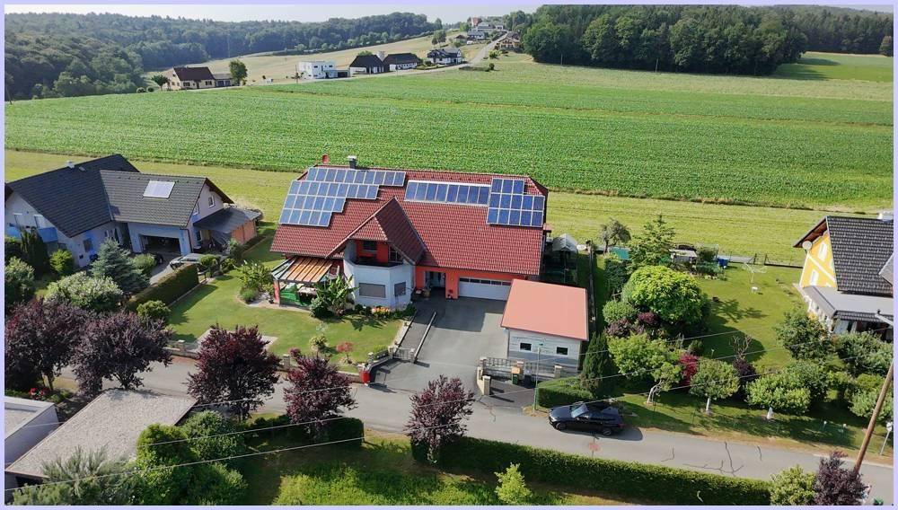 Weitläufige Luftaufnahme des Wohnhauses mit Photovoltaik und der ländlichen Umgebung mit Feldern.
