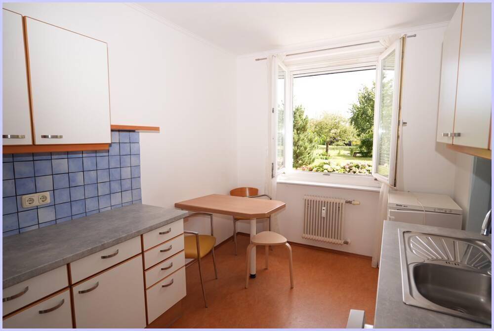 Geräumige Küche mit Essbereich, weißen Schränken und Fenster mit Blick auf den Garten.