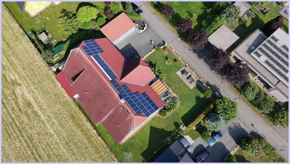 Senkrechte Luftaufnahme des Hauses mit Photovoltaikanlage, Garten und Zufahrt.