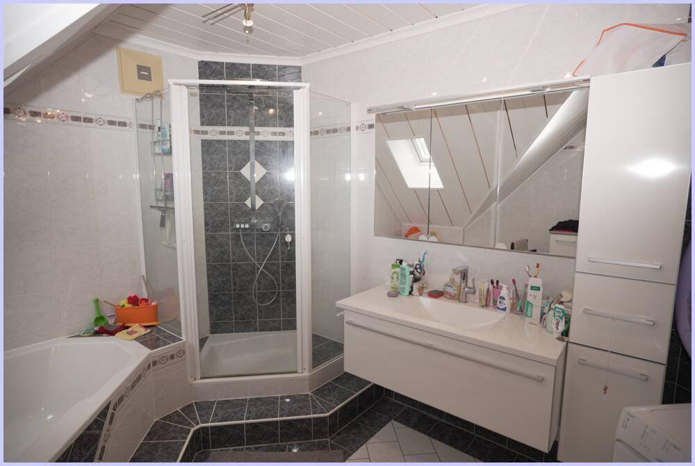Dachgeschoss-Badezimmer mit Badewanne, Duschkabine und Dachfenster für natürliches Licht.
