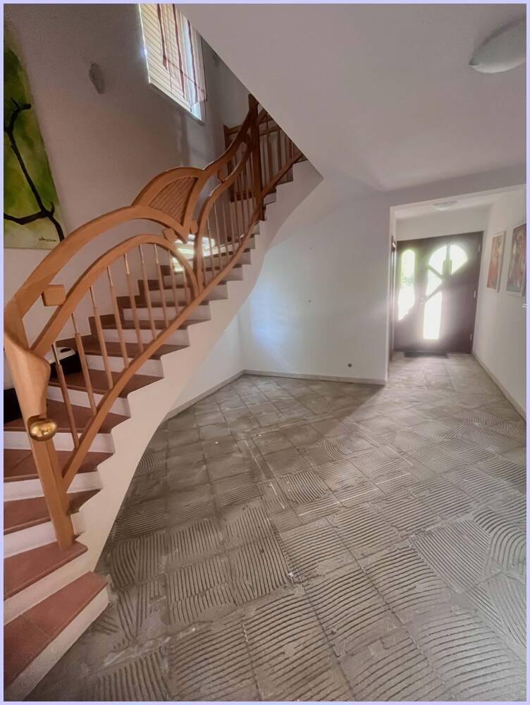 Heller Eingangsbereich mit eleganter Holztreppe und Fliesenboden, der auf eine Renovierung wartet.