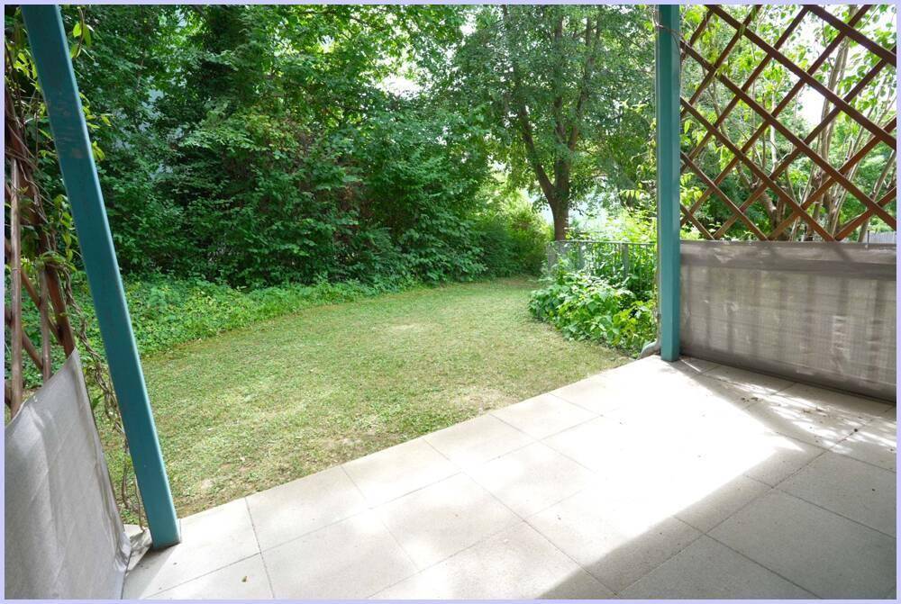 Gepflegter Garten mit Rasen und Bäumen, direkt an eine Terrasse angrenzend.