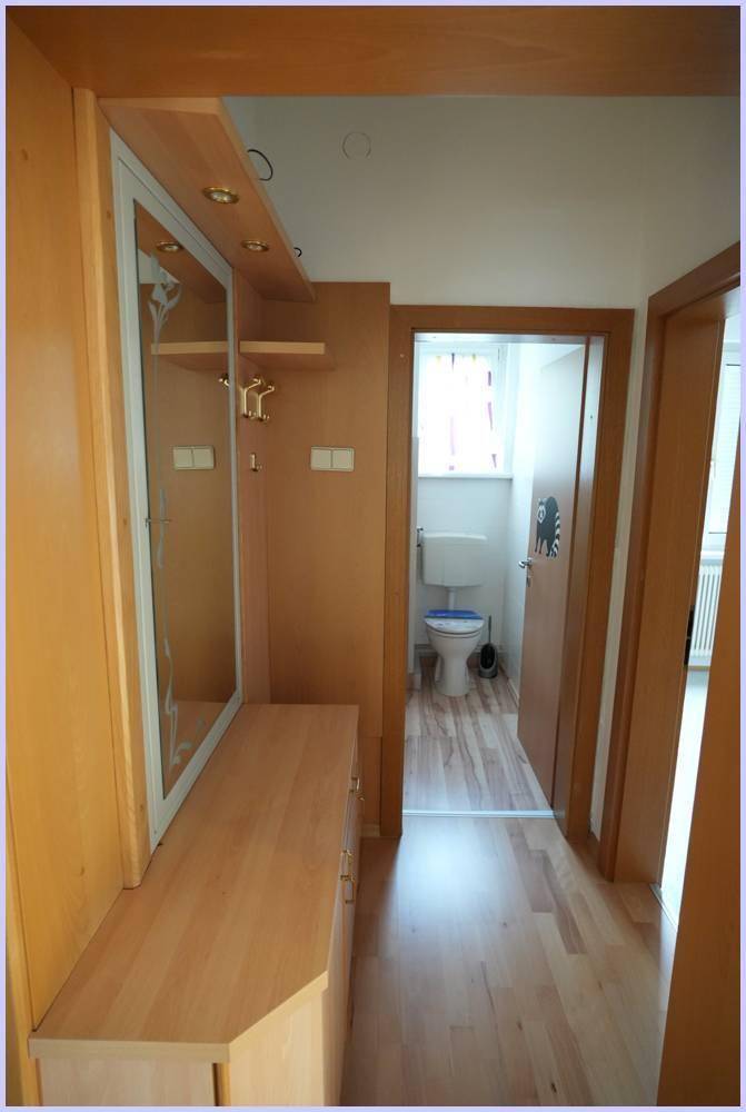 Flur mit integriertem Garderobenschrank und Spiegel, der zu einem WC führt.