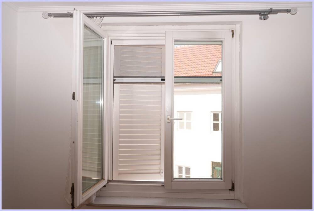 Geöffnetes Fenster mit Blick auf ein gegenüberliegendes Gebäude und Rollläden.