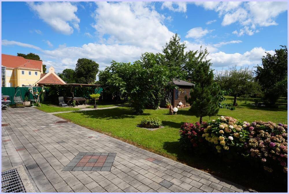 Großer, gepflegter Garten mit Rasenfläche, Bäumen und einem Gartenhaus.