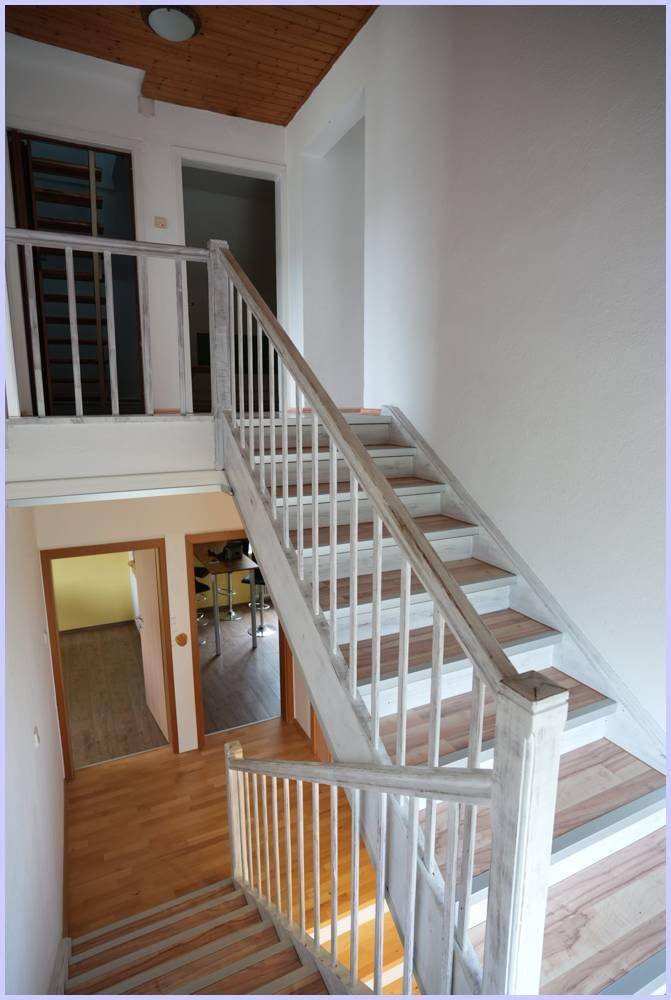 Fertige Holztreppe mit weißem Geländer, die verschiedene Ebenen des Hauses miteinander verbindet.