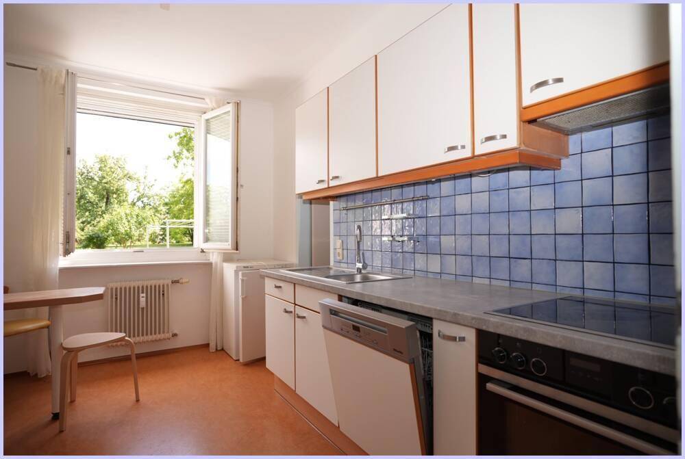 Funktionale Küche mit weißen Oberschränken, blauen Fliesen und integriertem Geschirrspüler.