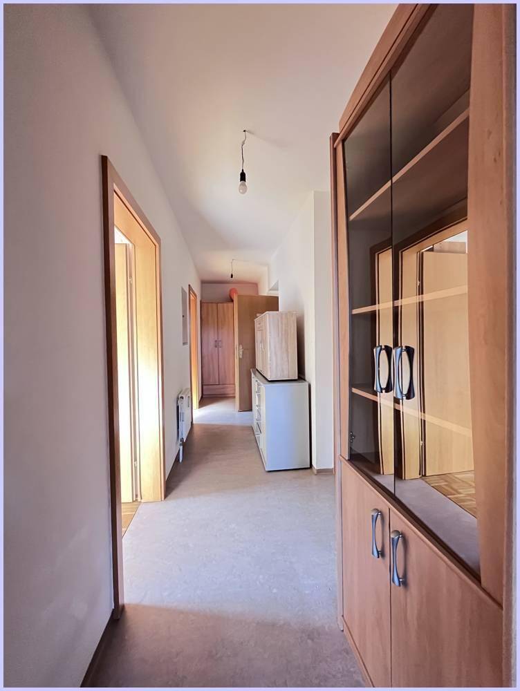 Heller Flur mit Holzmöbeln und Türen, der zu weiteren Räumen der Wohnung führt.
