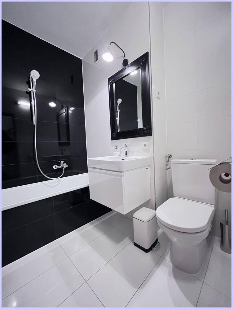 Modernes Badezimmer mit Badewanne, WC und Waschtisch, in elegantem Schwarz-Weiß-Design.