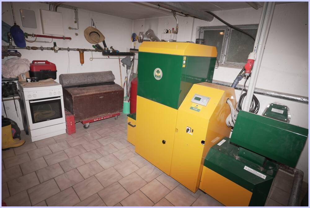 Heizungsraum mit Pelletheizung, Warmwasserspeicher und technischen Installationen.