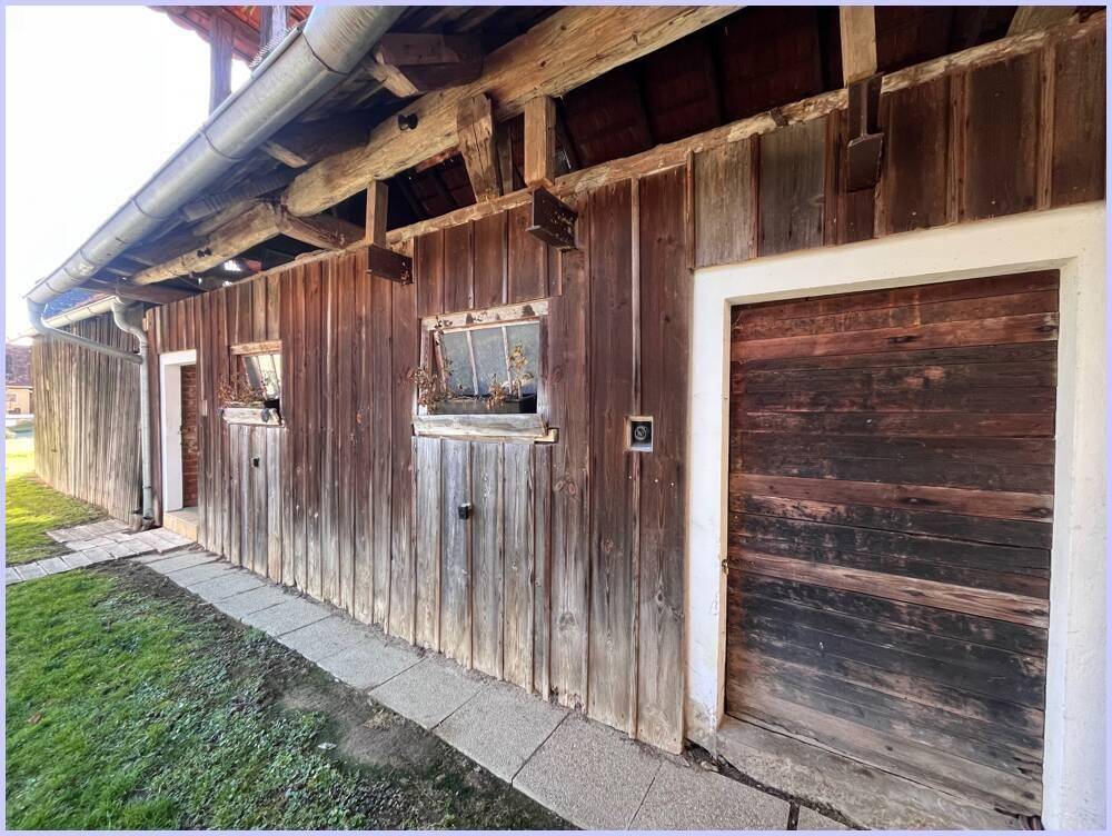 Detailansicht der rustikalen Holzfassade eines Nebengebäudes mit sichtbaren Holzbalken und Türen.