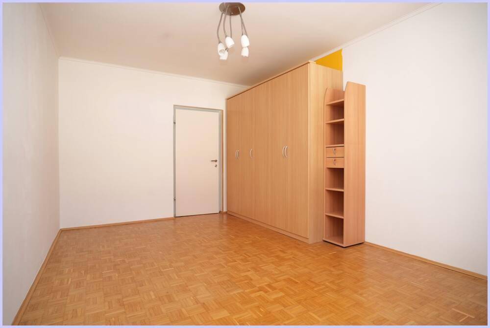 Helles Schlafzimmer mit Parkettboden und großem Kleiderschrank an der Wand.