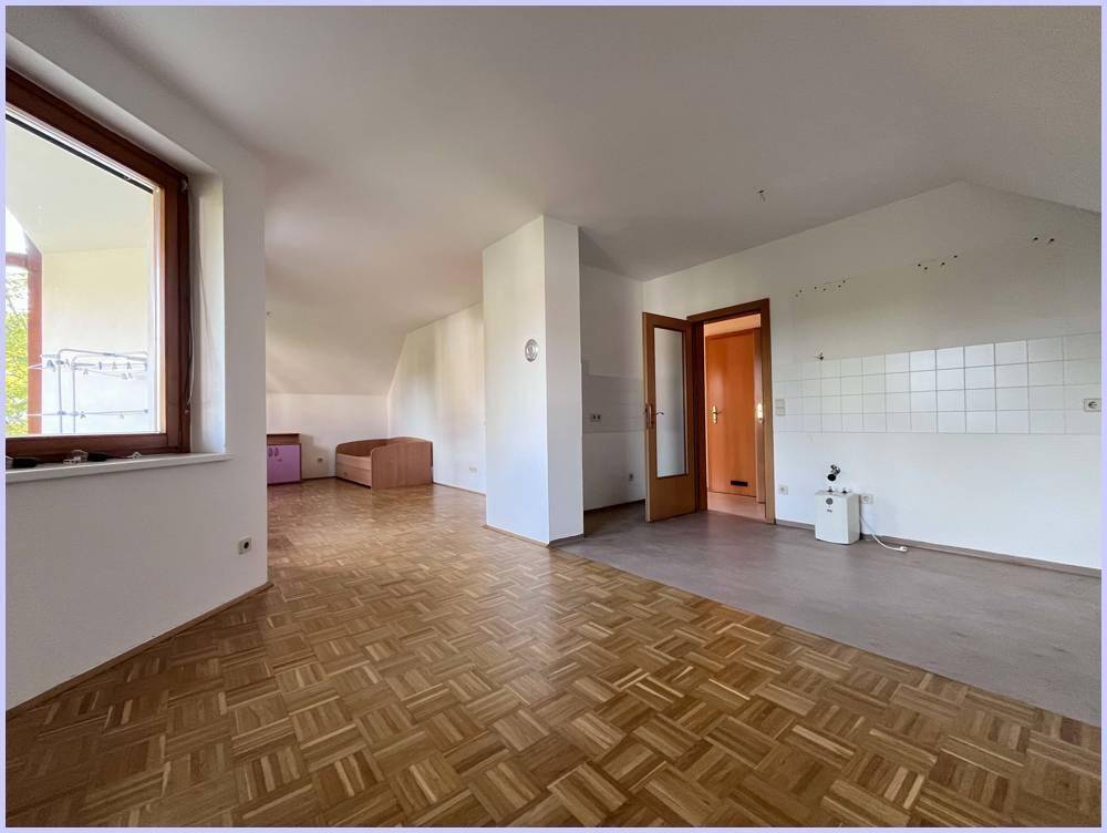 Geräumiger Dachgeschossraum mit Parkettboden, schrägen Wänden und Zugang zu einem Balkon.