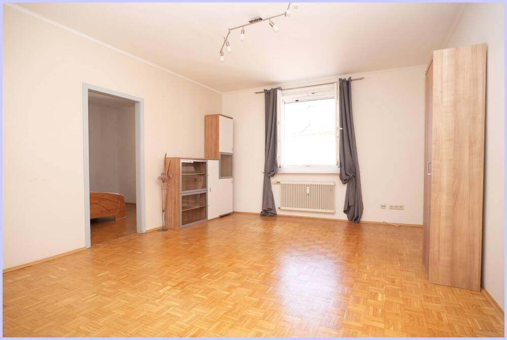 Geräumiges Wohnzimmer mit Parkettboden und Zugang zu einem weiteren Zimmer.