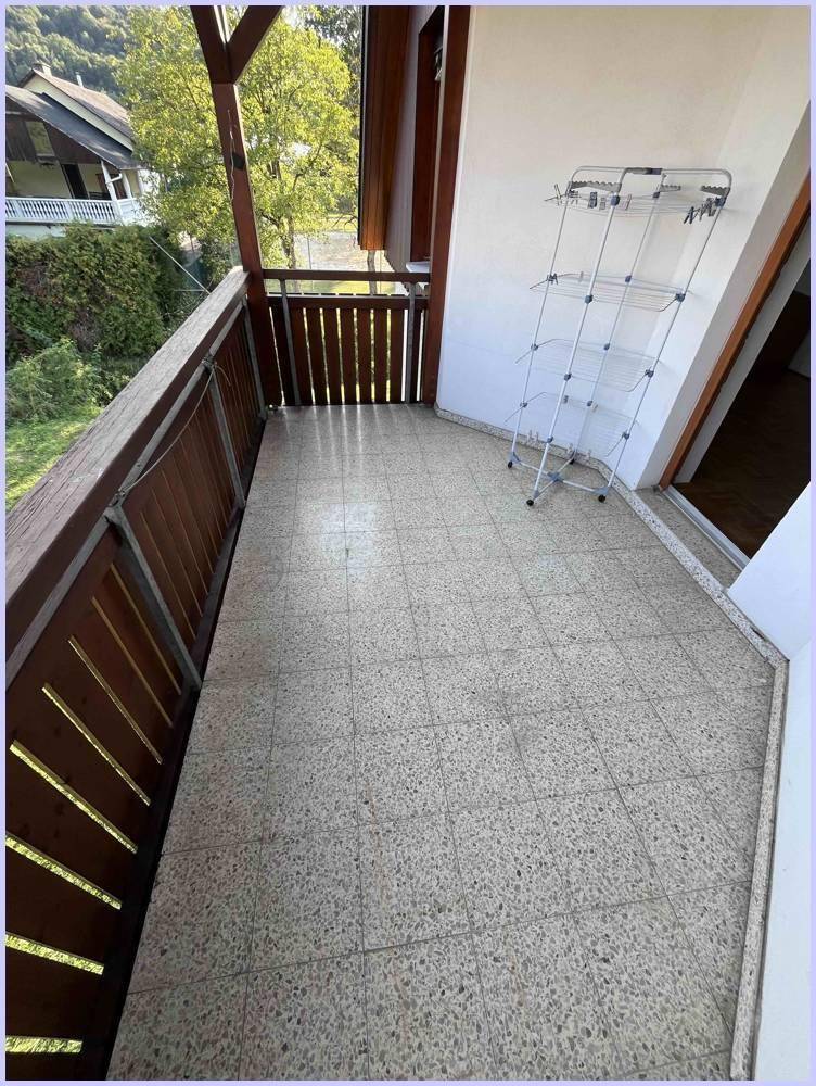 Balkon mit Fliesenboden und Holzgeländer, ausgestattet mit einem Wäscheständer für den täglichen Gebrauch.