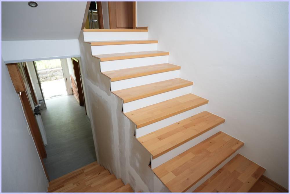 Neu installierte Holztreppe mit weißen Setzstufen, die zu einem oberen Stockwerk führt.
