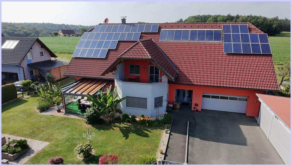 Drohnenansicht des Hauses mit großer Photovoltaikanlage, Garage und angrenzendem Wintergarten.