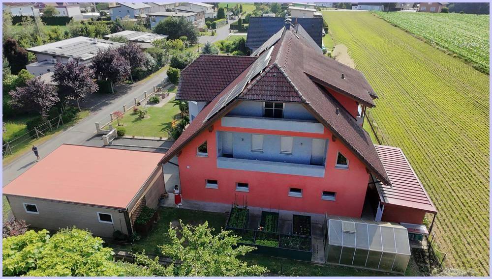 Rückansicht des Hauses aus der Vogelperspektive mit Garten und Gewächshaus.