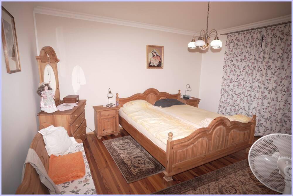 Schlafzimmer mit traditionellem Holzdoppelbett, Nachttischen und Holzboden, in einem gemütlichen Stil.
