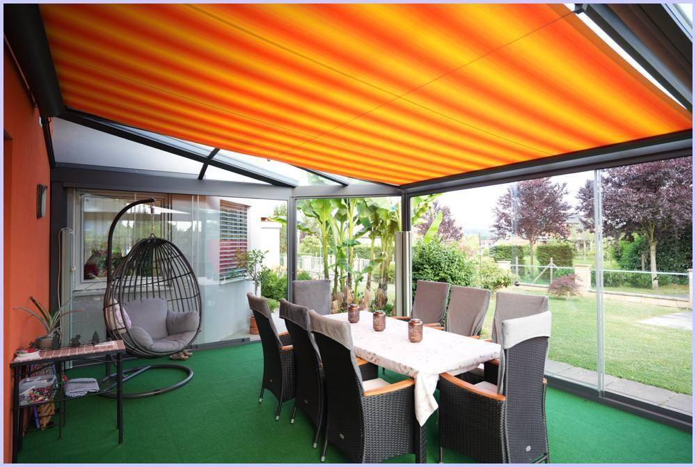 Gemütlicher Wintergarten mit Esstisch, Hängesessel und Blick in den Garten.