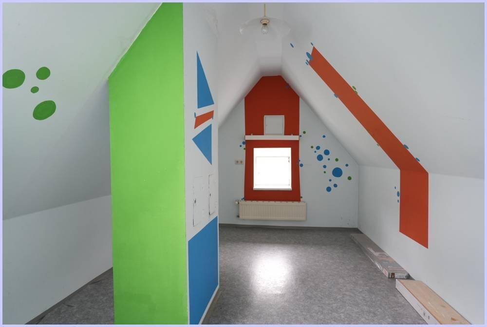 Dachzimmer mit schrägen Wänden, farbenfrohen geometrischen Mustern und einem Fenster.