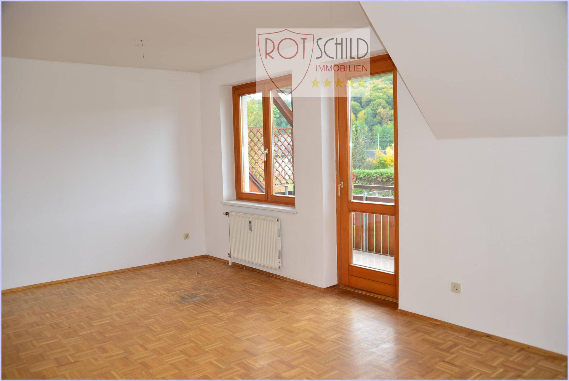 Helles Schlafzimmer mit Parkettboden, Dachschräge und Zugang zum Balkon.