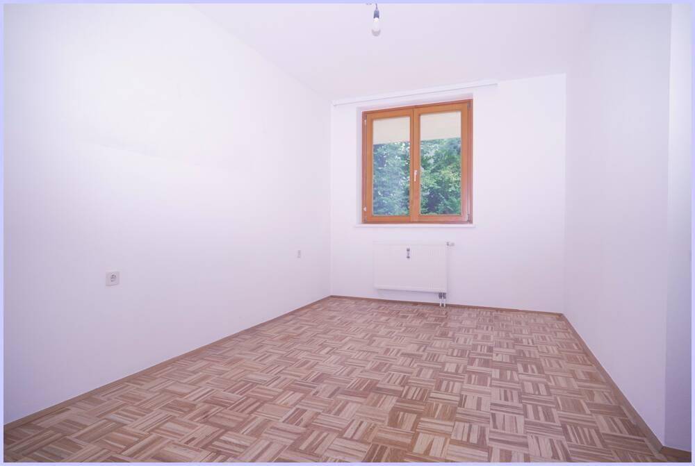 Ruhiges Zimmer mit Parkettboden und Fenster, das viel Tageslicht hereinlässt.
