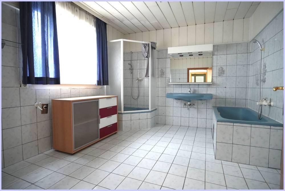 Badezimmer mit blauer Badewanne, Waschbecken, Duschkabine und weißen Fliesen.
