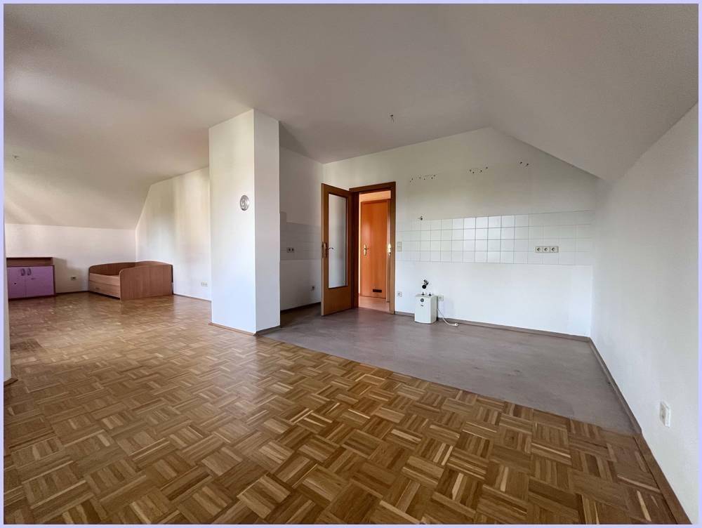 Großer, heller Raum im Dachgeschoss mit gemischtem Bodenbelag und vorbereiteter Wandfläche.