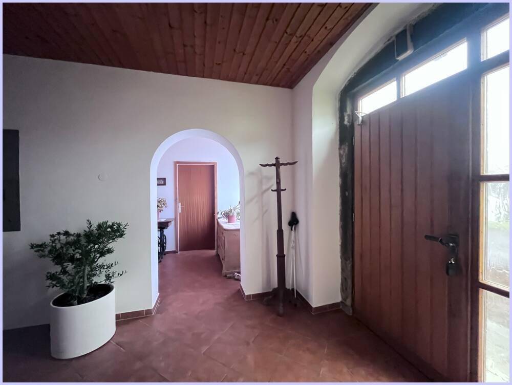 Heller Eingangsbereich mit Holztür, Terrakottafliesen und einer Holzdecke, die eine warme Atmosphäre schafft.