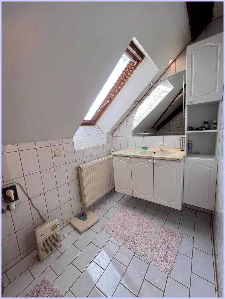 Helles Badezimmer im Dachgeschoss mit Waschbecken, Spiegelschrank und Dachfenster für Tageslicht.