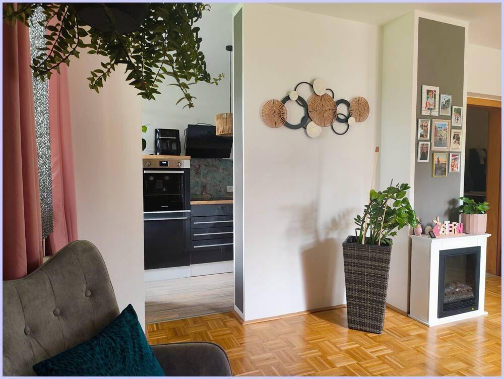 Wohnzimmer mit Parkettboden und Blick in die moderne Küche.