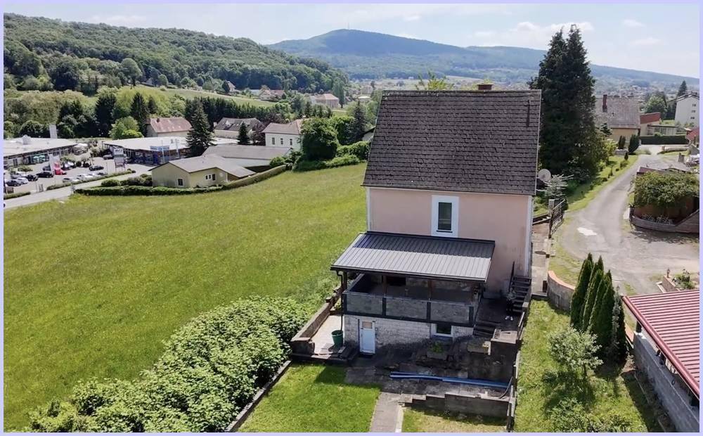 Rückseite des Hauses mit Garten, Balkon und Blick auf die umliegende Natur.