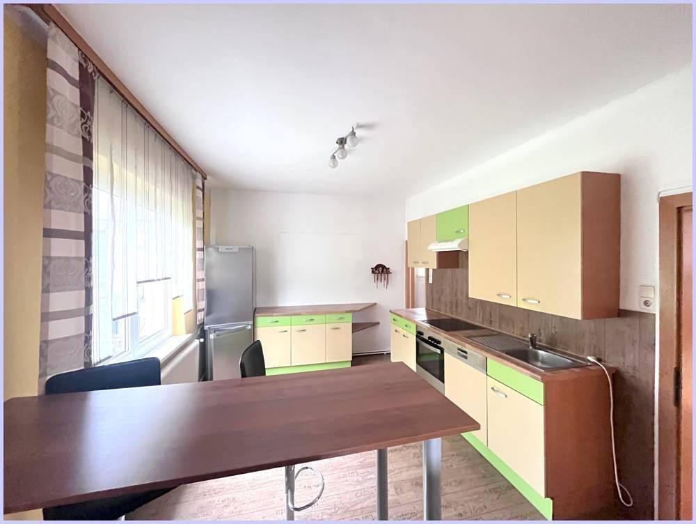 Geräumige Küche mit Esstisch, farbigen Schränken und Fenster für natürliches Licht.